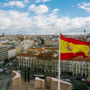 Letecký pohľad na Madrid so španielskou vlajkou v popredí. Španielčina prepája Európu s Latinskou Amerikou a otvára možnosti cestovania aj práce.