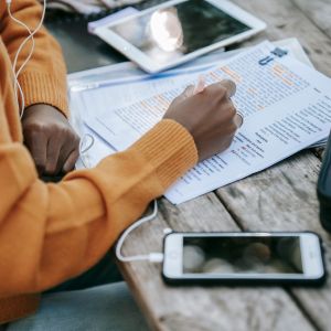 Človek telefonuje v angličtine so slúchadlami v ušiach a poznámkami pred sebou.